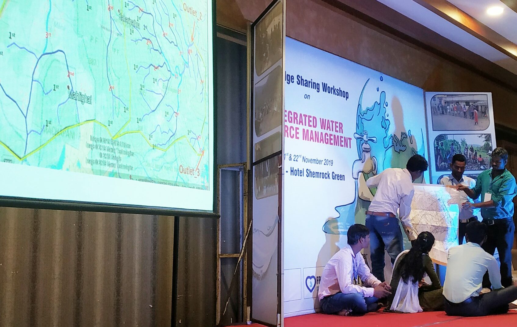 Indian NGO workers on stage at a knowledge sharing meeting in India with a screen behind them that reads Integrated Water Resource Management