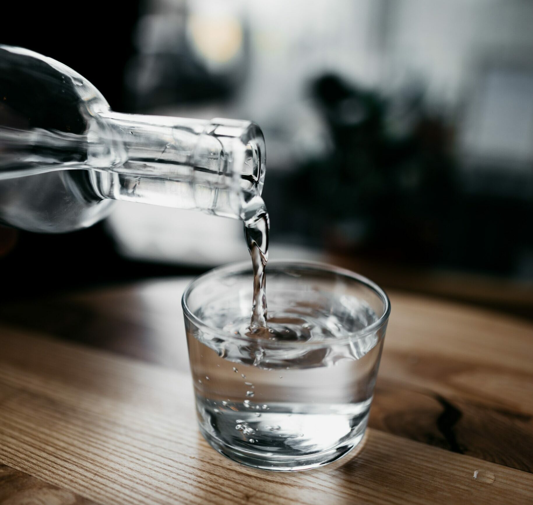 water pouring from glass bottle into glass on table